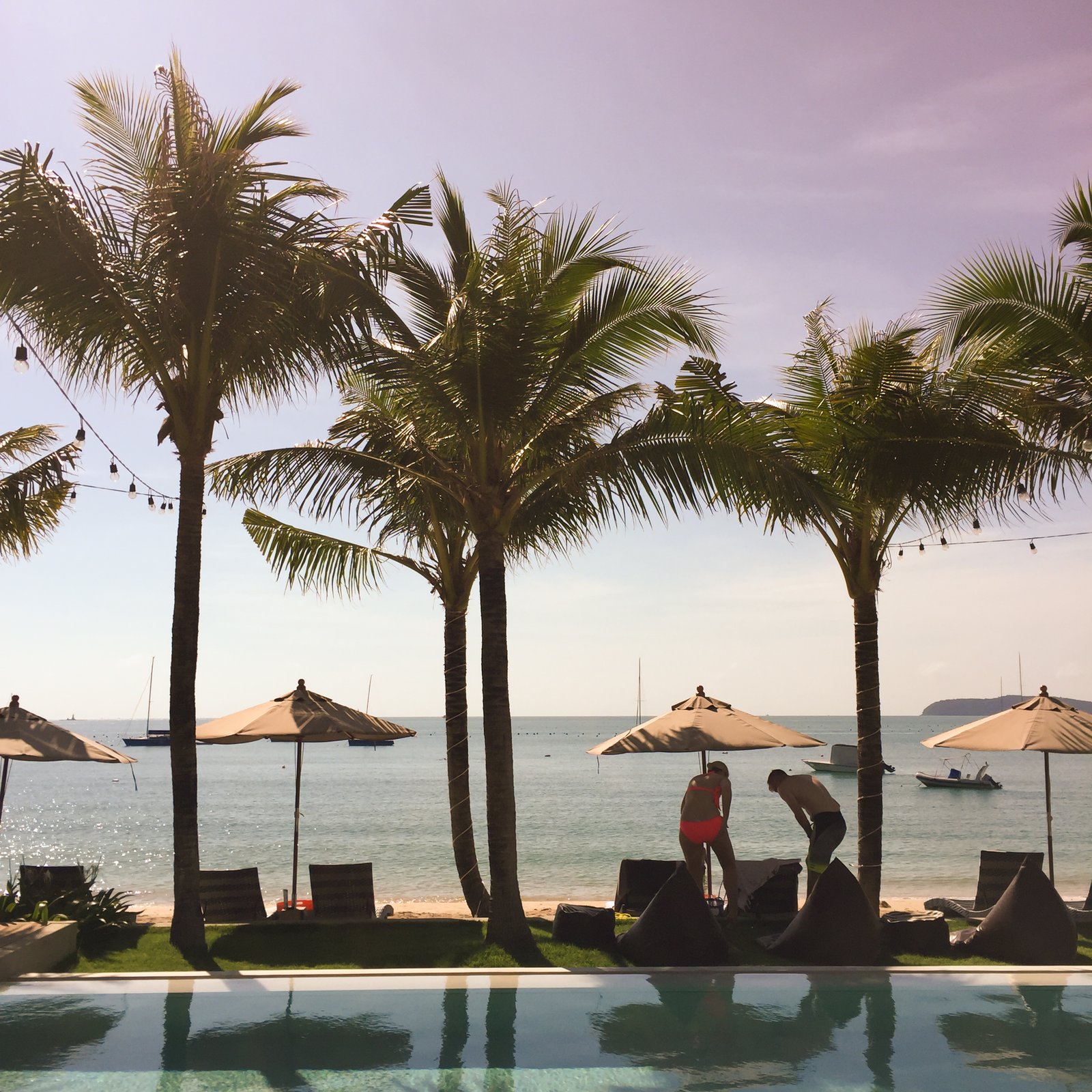 Delicate sunset at the Andaman Sea. A popular resort on the island of Koh Samui. Palm trees reflected in smooth water of the pool on the beach. Vintage effect style pictures.